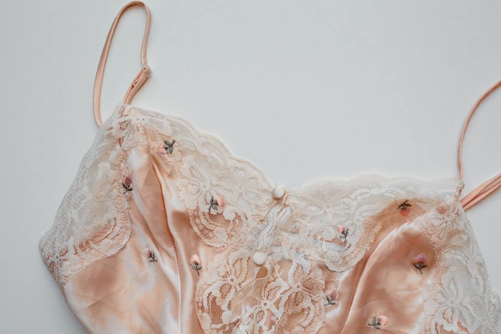Haut de lingerie en dentelle rose délicate sur fond blanc.